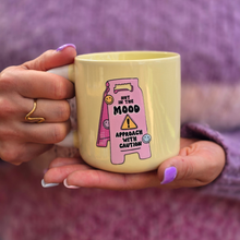 Load image into Gallery viewer, Lemon ceramic mug featuring a pink caution sign with the funny quote "Not in the Mood, Approach with Caution", held in both hands against a soft purple background.
