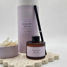 Load image into Gallery viewer, Luxury reed diffuser home fragrance in 100ml amber glass bottle with black reeds.  Presented in lilac cylinder box ready for gifting. Fragrance Kakadu plum.
