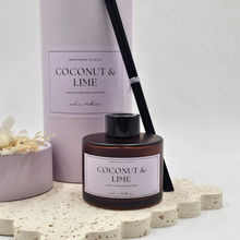 Load image into Gallery viewer, Luxury reed diffuser home fragrance in 100ml amber glass bottle with black reeds.  Presented in lilac cylinder box ready for gifting. Fragrance Coconut &amp; Lime
