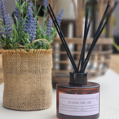 Diffuser with reeds and a decorative container on a blurred background