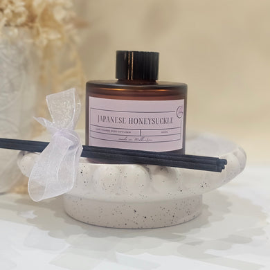 A diffuser with a bottle and sticks on a textured surface