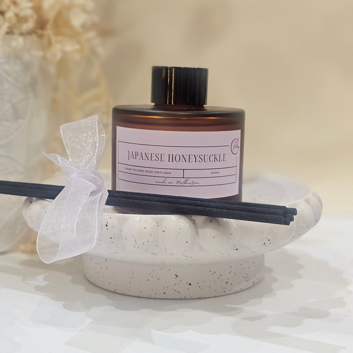 A diffuser with a bottle and sticks on a textured surface
